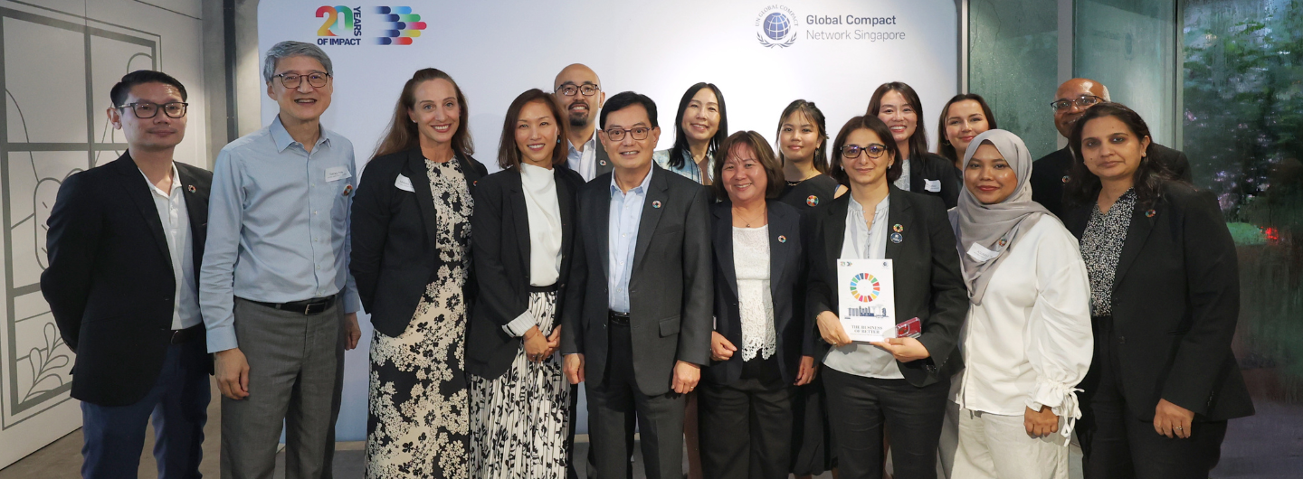 Group of diverse people posing in front of "UN Global Compact Network Singapore" logo.